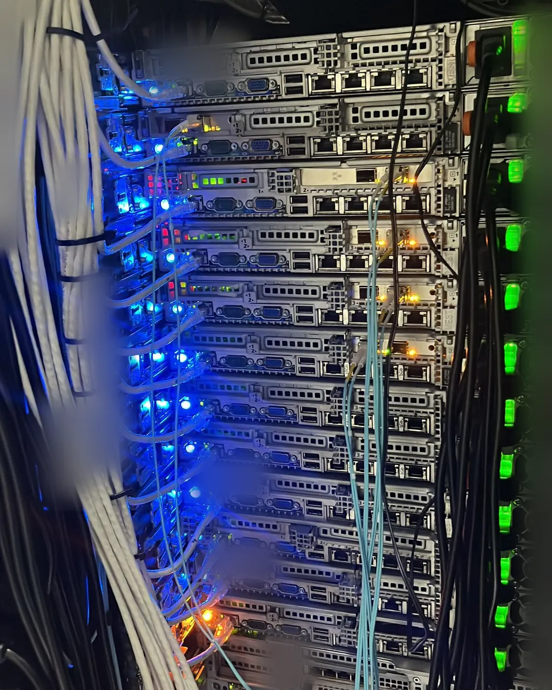 The back of one of our server racks: rows of servers with blue status lights and bundled network cables